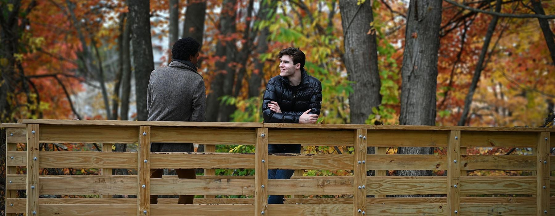 a man and a woman standing on a wooden fence